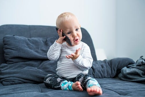 A young boy babbling on a mobile phone. He is too young to have a meaningful discussion.